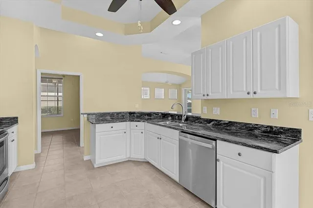 a kitchen with granite countertop a sink and white cabinets