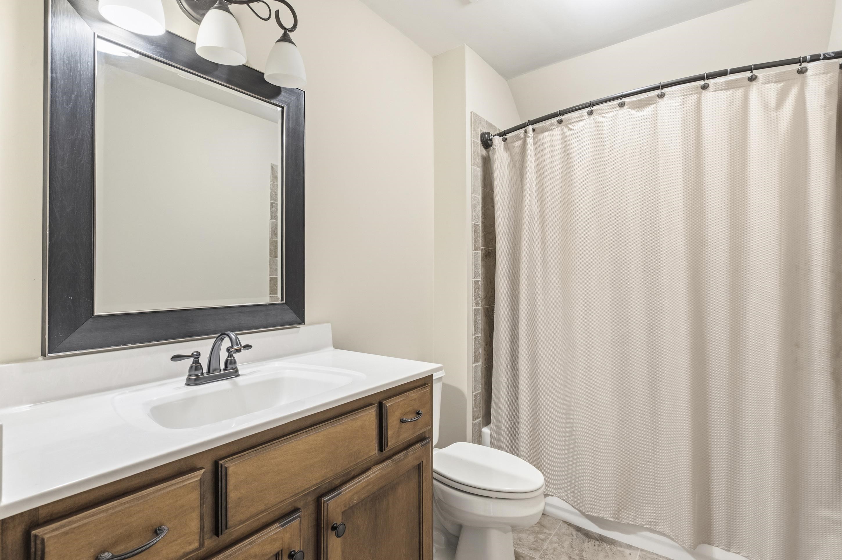 1795 Gaines Road Hernando, MS 38632 - Photo 26 of 40 a bathroom with a sink a toilet and shower curtain