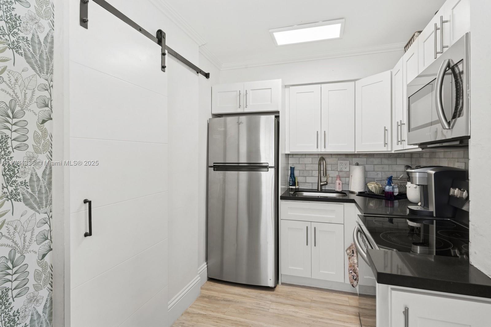 8701 Southwest 141st Street, Unit A5 Palmetto Bay, FL 33176 - Photo 6 of 19 a kitchen with stainless steel appliances granite countertop a refrigerator a stove and a sink with wooden floor
