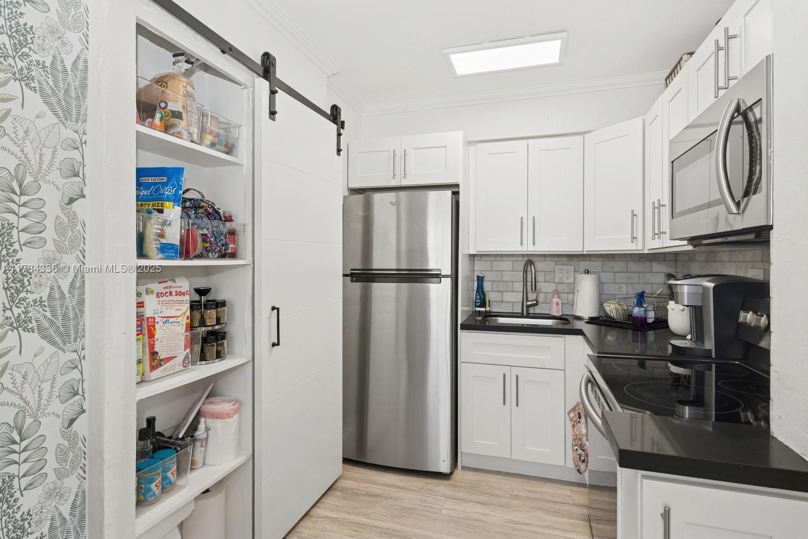 8701 Southwest 141st Street, Unit A5 Palmetto Bay, FL 33176 - Photo 7 of 19 a kitchen with stainless steel appliances granite countertop a refrigerator and a stove top oven