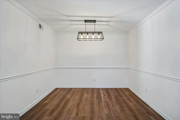 a view of an empty room with wooden floor and window