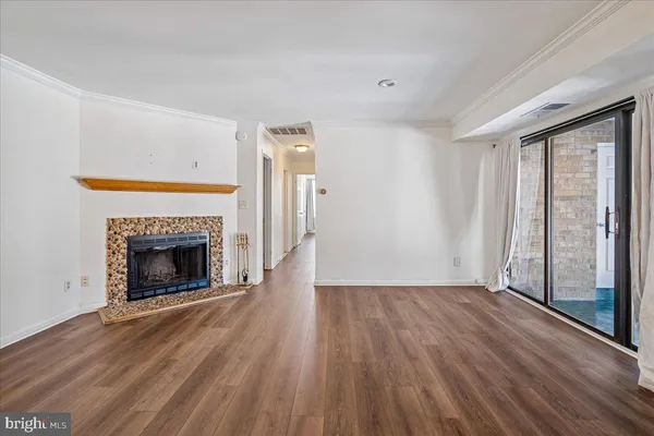an empty room with wooden floor fireplace and windows