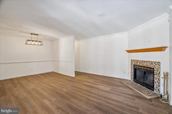 a view of an empty room with wooden floor and a fireplace