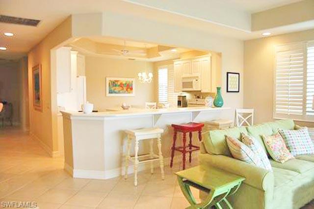 6017 Trophy Drive, Unit 601 Naples, FL 34110 - Photo 4 of 24 a living room with furniture a flat screen tv and a large window