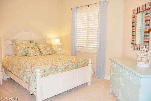 6017 Trophy Drive, Unit 601 Naples, FL 34110 - Photo 8 of 24 a large bed sitting in a bedroom next to a window