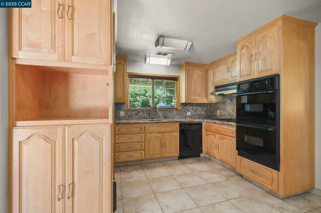 a kitchen with granite countertop white cabinets and stainless steel appliances