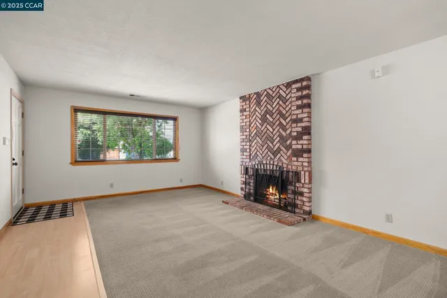 a view of an empty room with a window and a fireplace