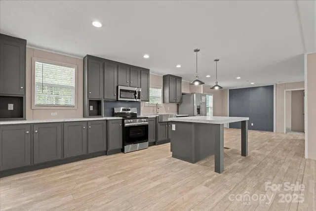 a large kitchen with stainless steel appliances kitchen island a large counter top and a wooden floors