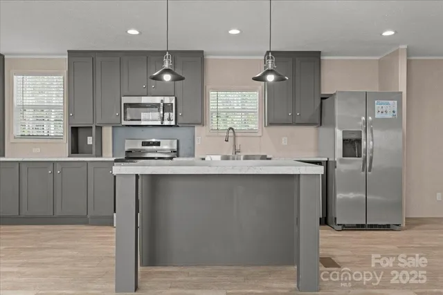 a kitchen with stainless steel appliances granite countertop a sink a stove a refrigerator and island with wooden floor