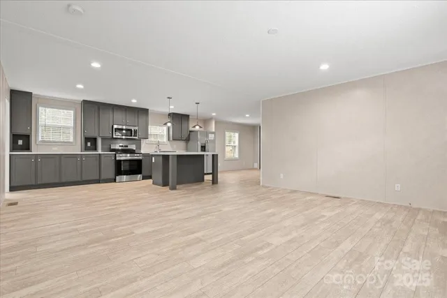a view of kitchen with kitchen island a sink wooden floor and view living room