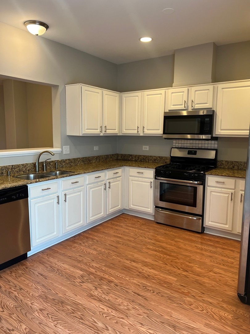 3393 Ravinia Circle Aurora, IL 60504 - Photo 5 of 14 a kitchen with stainless steel appliances a stove sink microwave and cabinets