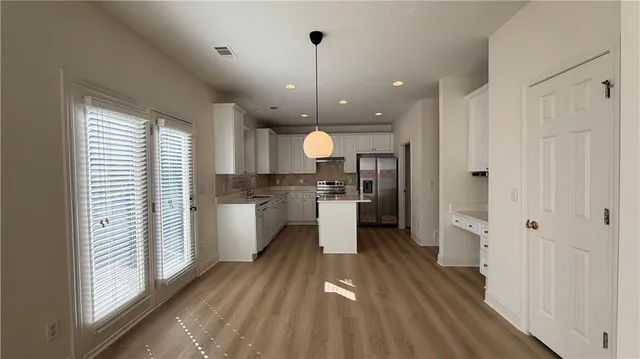 a kitchen with stainless steel appliances granite countertop a stove a refrigerator and a white cabinets