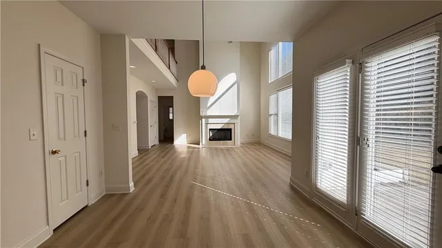 a large white kitchen with granite countertop a stove a sink a refrigerator and white cabinets with wooden floor