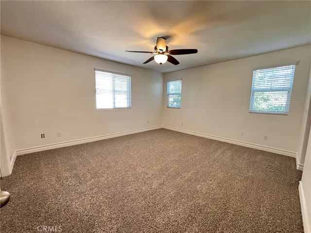 an empty room with windows and fan