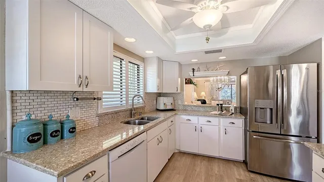 a kitchen with a sink stainless steel appliances granite countertop a refrigerator a sink a stove and cabinets
