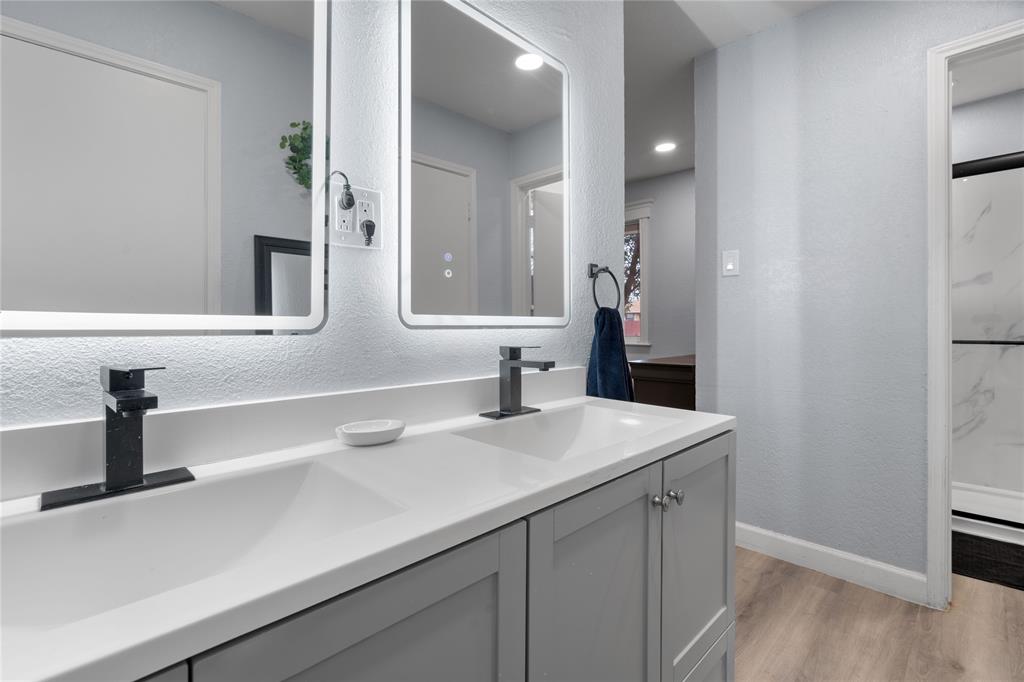 7629 Cedarhill Road Watauga, TX 76148 - Photo 26 of 26 Dual vanity with integrated sinks, two backlit mirrors, matte black fixtures, and wood-finish flooring