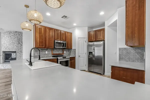 a kitchen with granite countertop a refrigerator a stove a sink a counter space and cabinets