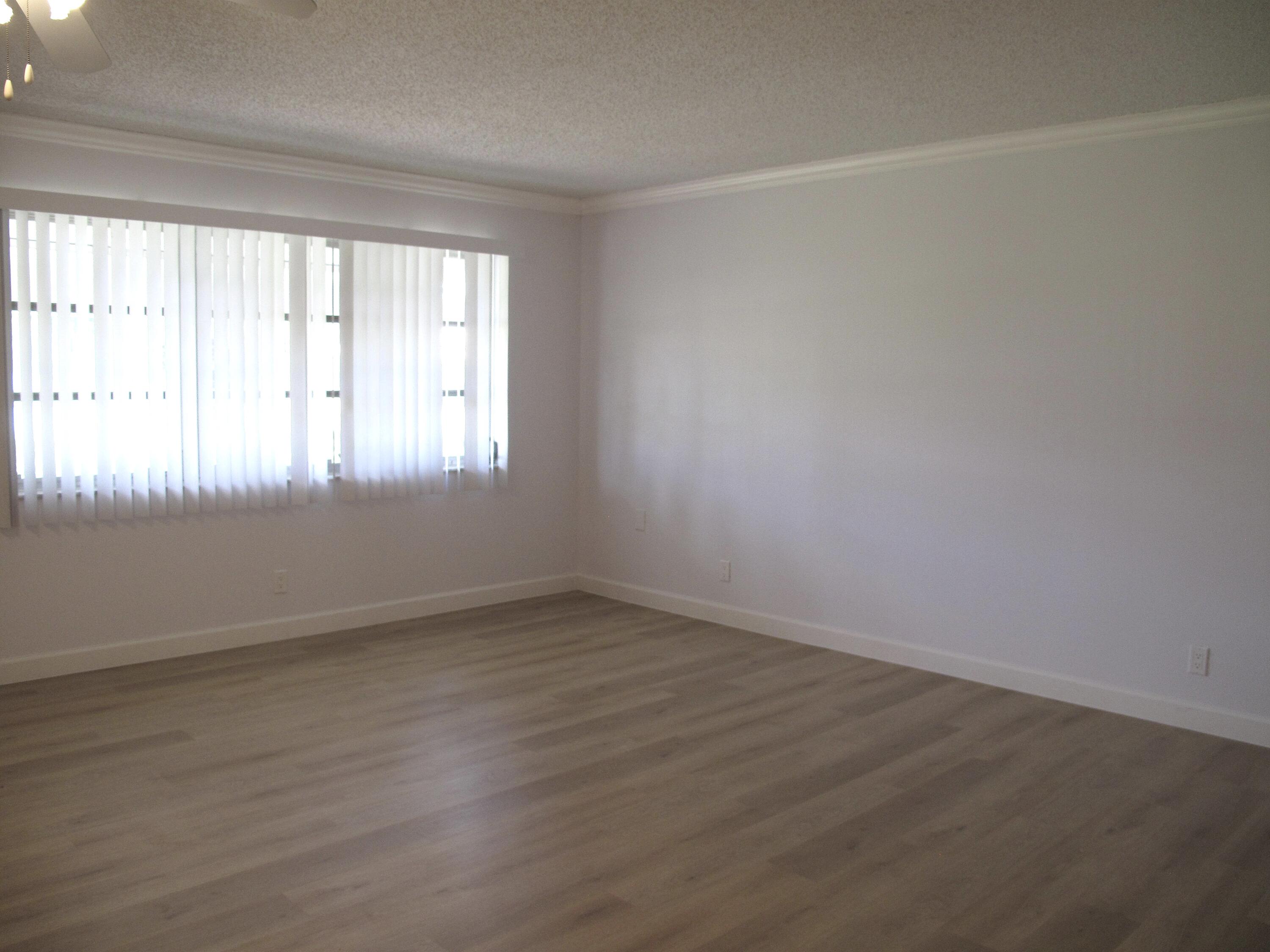 1102 North Drive, Unit C Delray Beach, FL 33445 - Photo 15 of 36 an empty room with wooden floor and windows