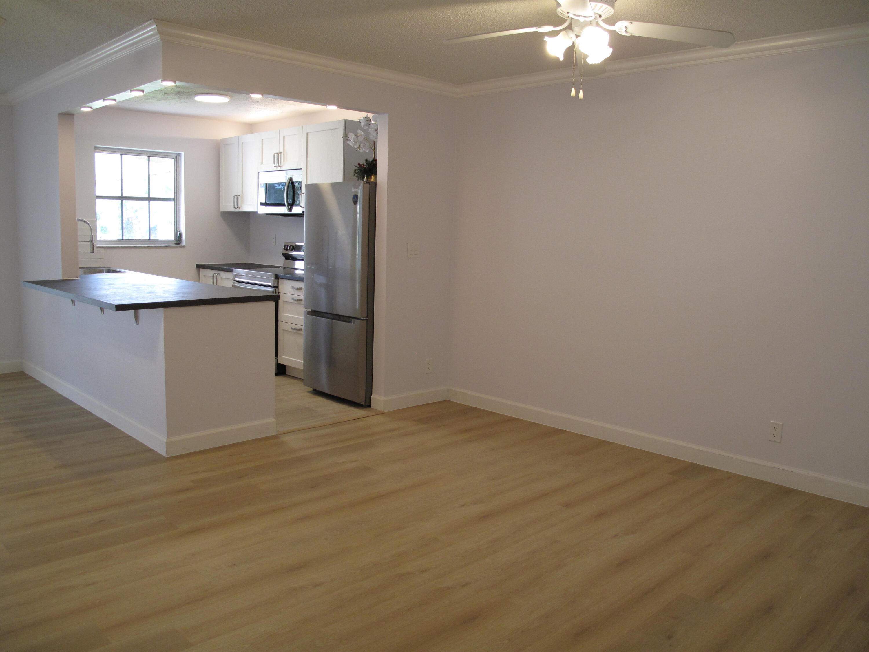 1102 North Drive, Unit C Delray Beach, FL 33445 - Photo 2 of 36 a view of a kitchen with a sink cabinets and wooden floor