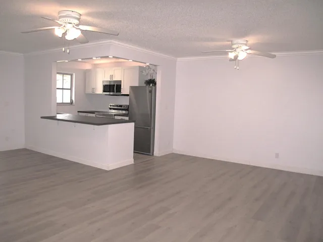a view of a kitchen with a sink a ceiling fan and wooden floor
