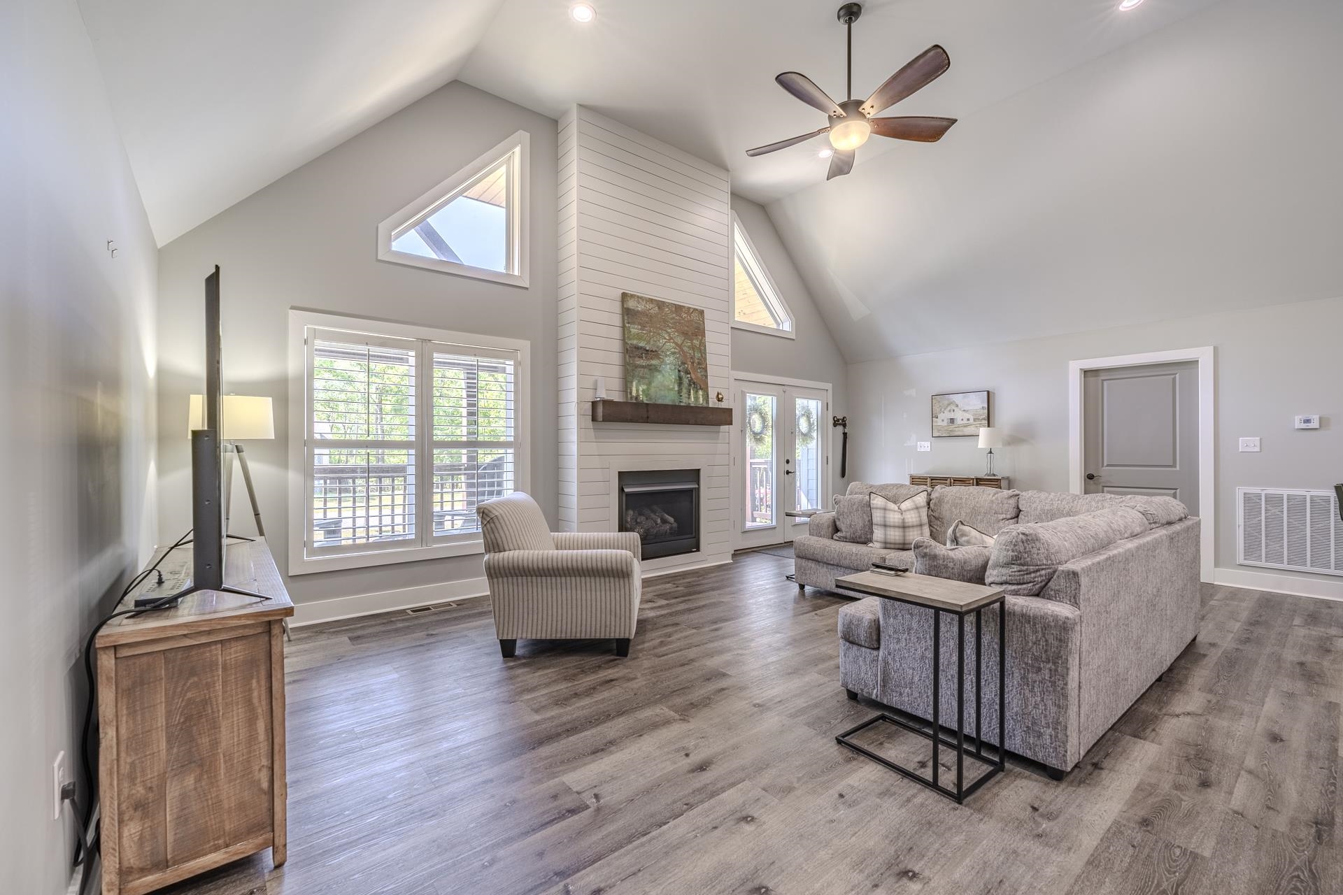 120 Rustic Trail Counce, TN 38326 - Photo 12 of 29 Living room with ceiling fan, a high ceiling, a large fireplace, plenty of natural light, and wood finished floors