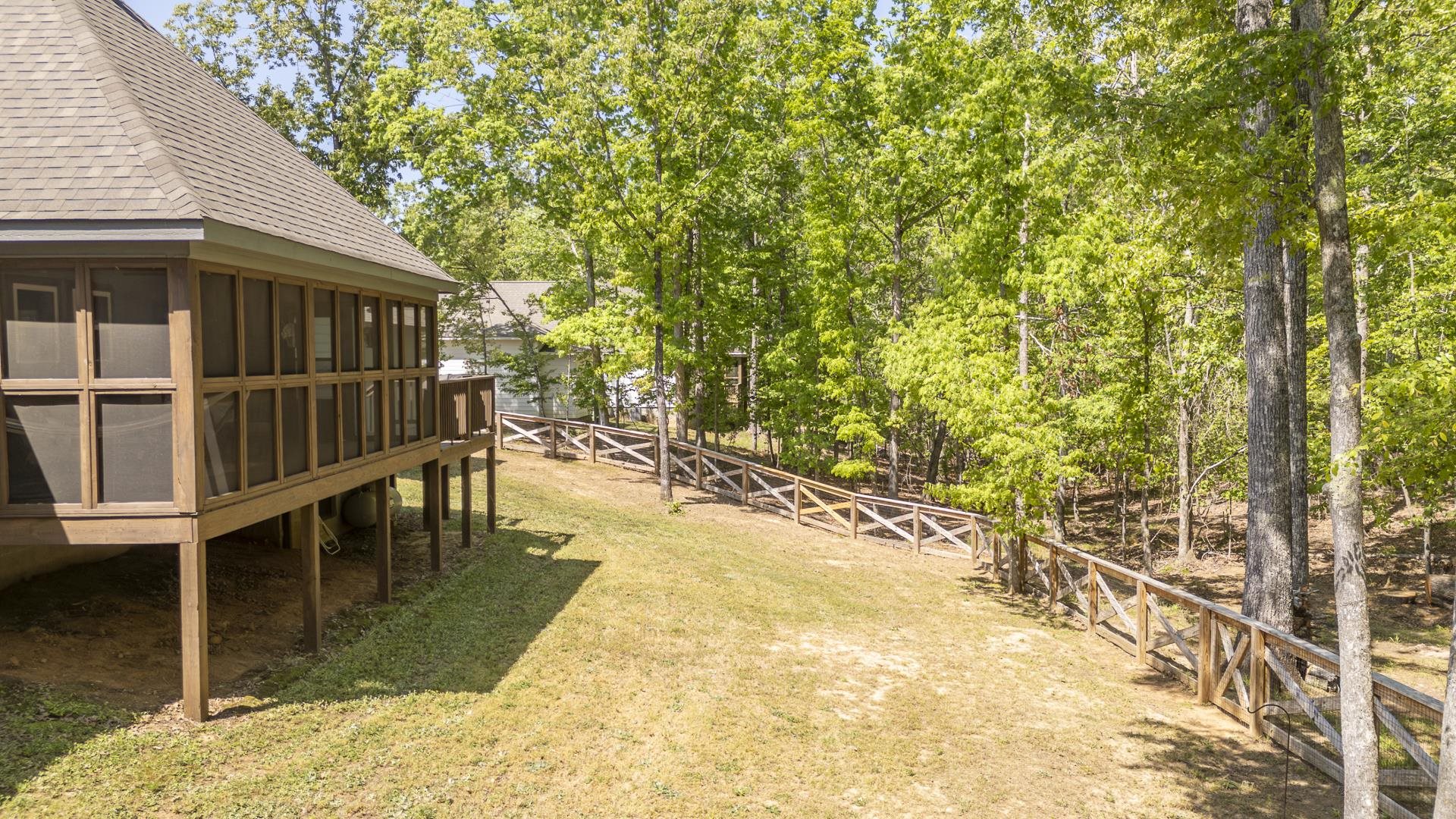 120 Rustic Trail Counce, TN 38326 - Photo 5 of 29 Fenced backyard with a sunroom, a wooden deck, and view of wooded area