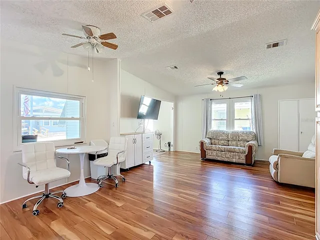 a view of a livingroom with furniture a ceiling fan and windows
