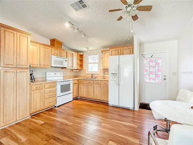 a kitchen with a refrigerator cabinets and wooden floor
