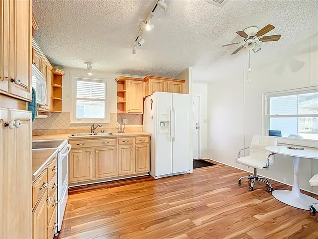 a large white kitchen with a window and refrigerator