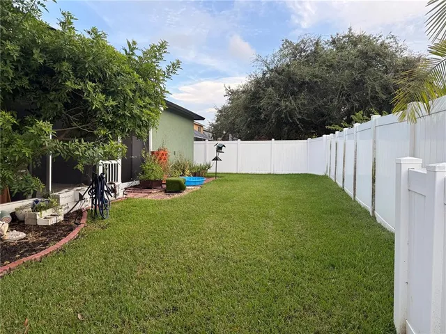 a view of a backyard with table and chairs potted plants and wooden fence