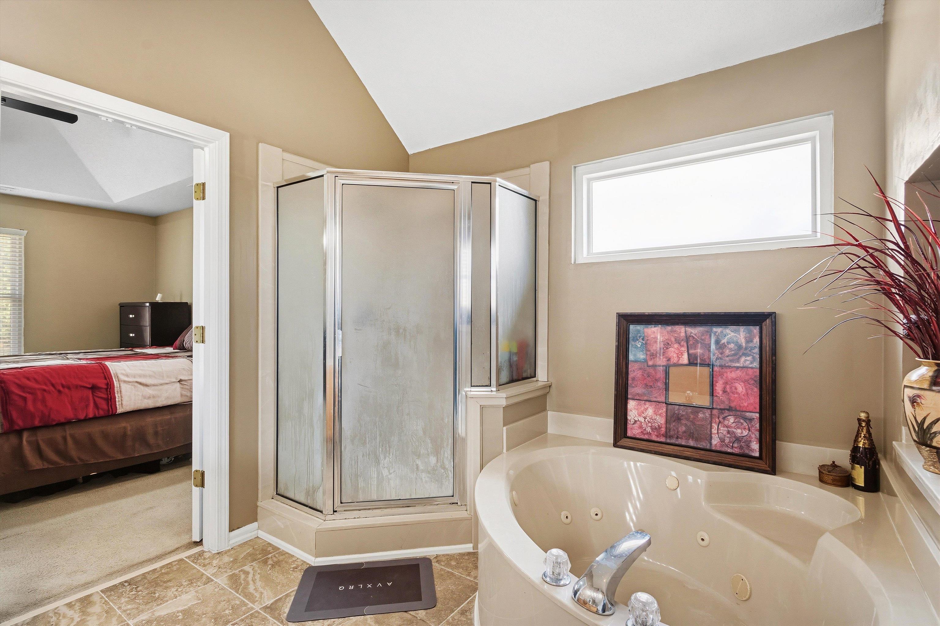 7779 Windy Willow Road Memphis, TN 38125 - Photo 16 of 30 Bathroom featuring a built-in jetted tub, a separate glass-enclosed shower, tiled flooring, and a transom window