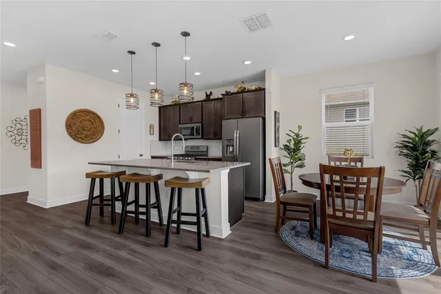 a kitchen with stainless steel appliances a table chairs refrigerator and microwave