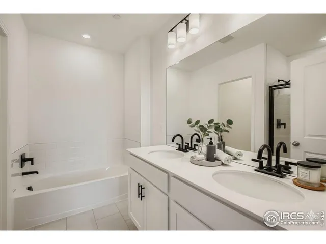 a bathroom with a sink double vanity granite tub shower and a mirror