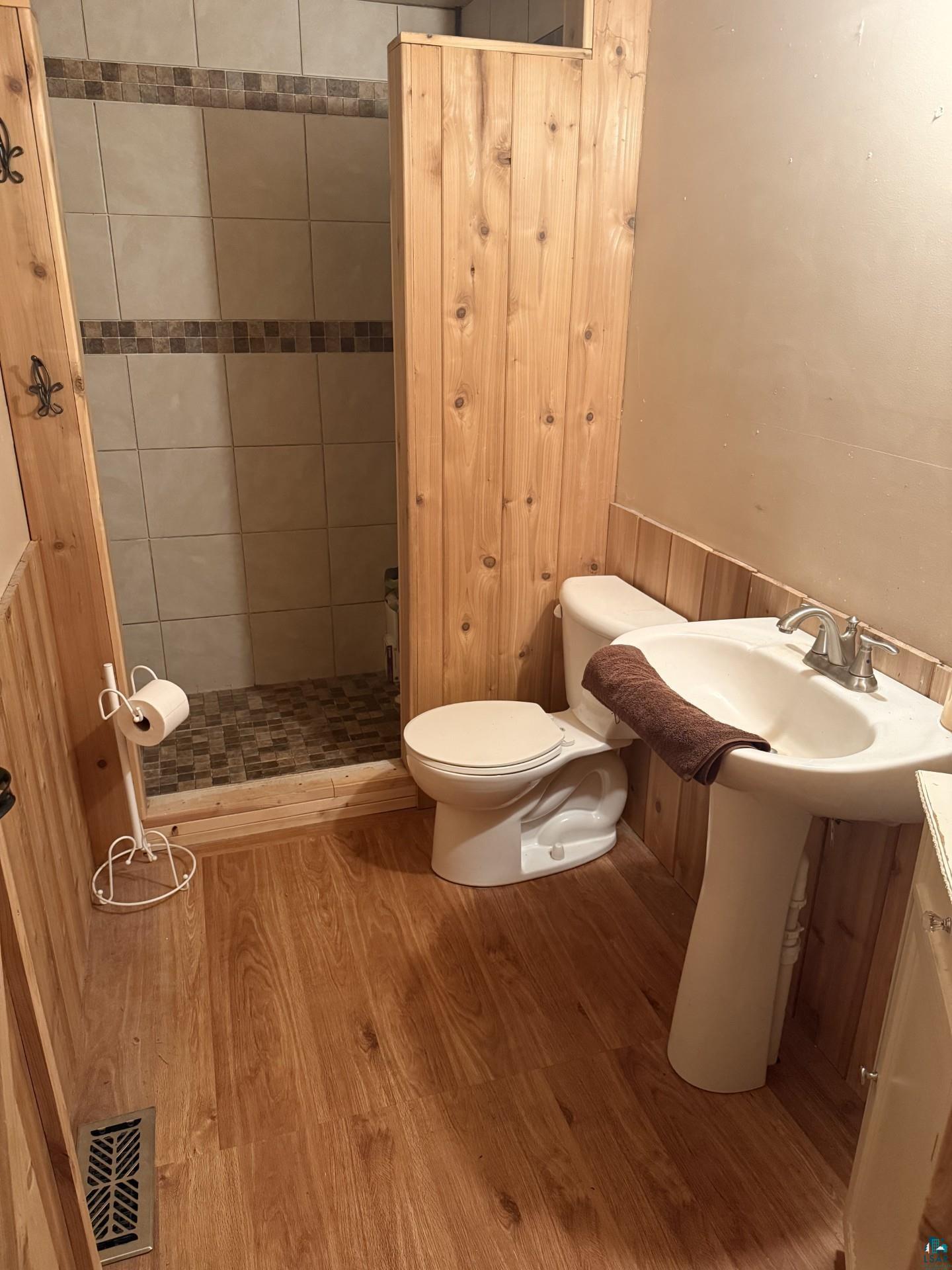 124 Nynas Road Esko, MN 55733 - Photo 7 of 14 Wood-finish flooring with a pedestal sink, toilet, and shower with tiled walls