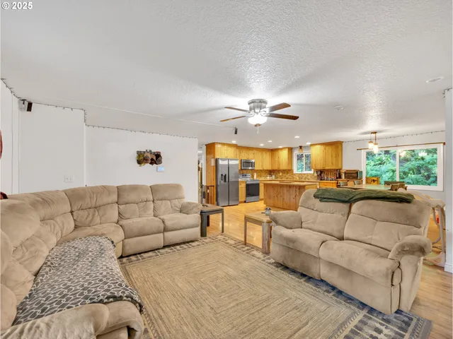 a living room with stainless steel appliances granite countertop furniture wooden floor and a window