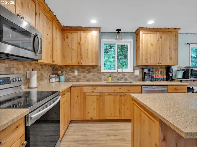 a kitchen with stainless steel appliances granite countertop a stove a sink dishwasher a refrigerator and white cabinets with wooden floor