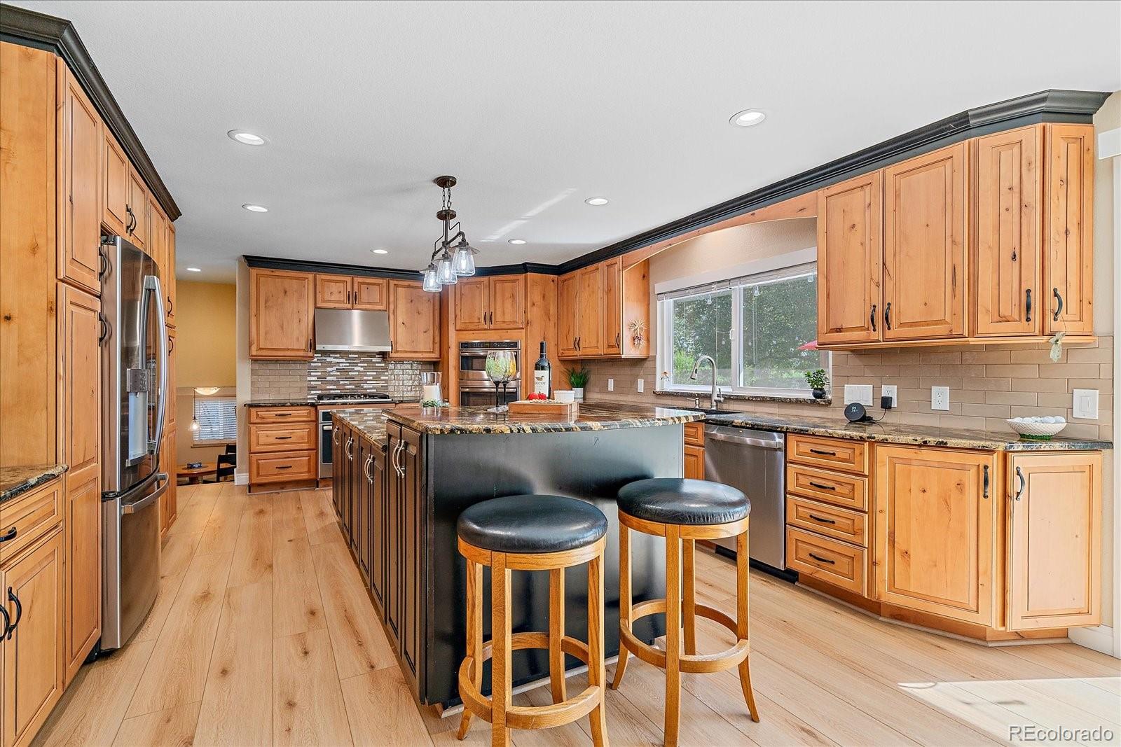 930 Reed Court Lakewood, CO 80214 - Photo 7 of 41 a kitchen with stainless steel appliances granite countertop a refrigerator a sink dishwasher a stove and a dining table with wooden floor