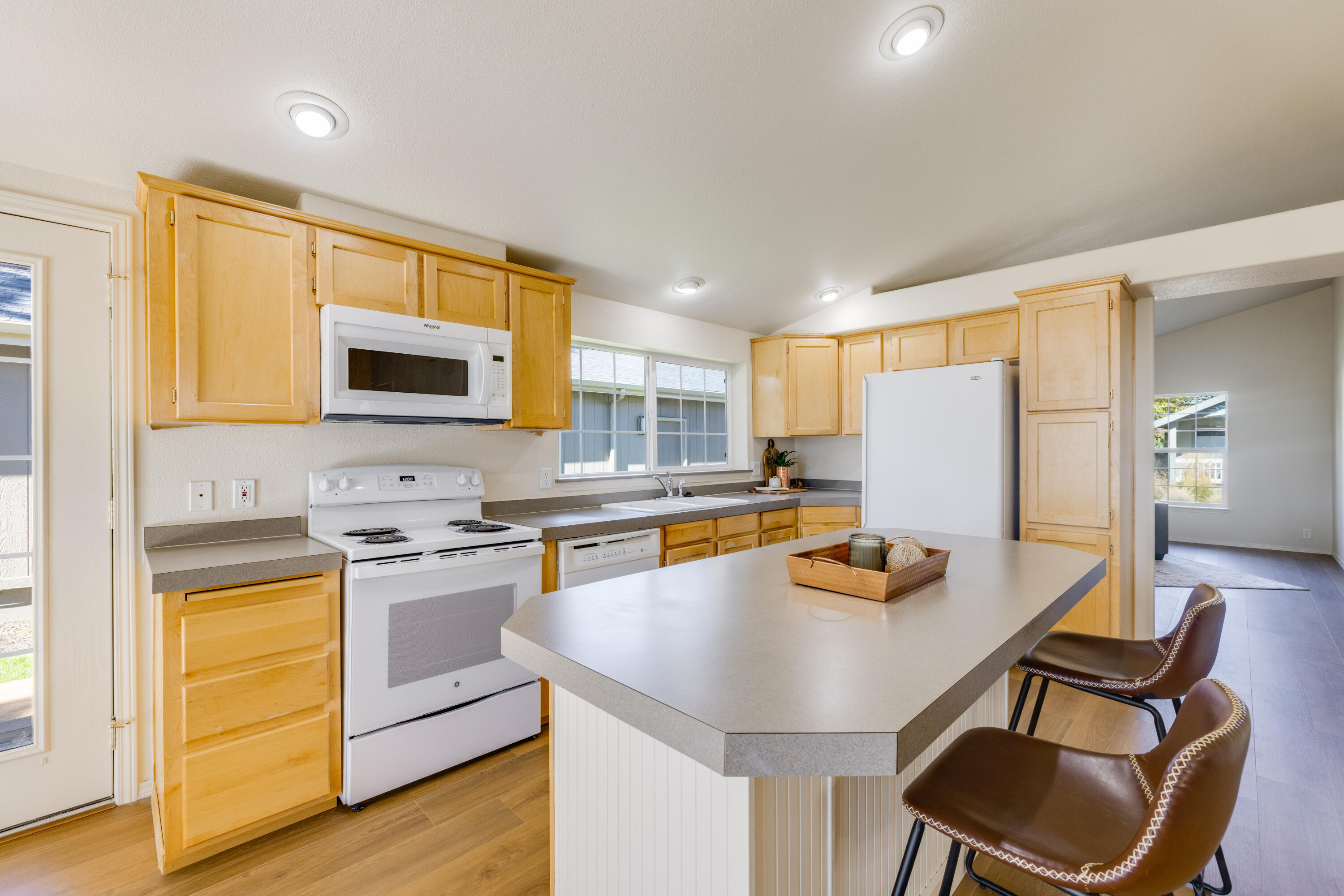 278 North Wheeler Loop Sisters, OR 97759 - Photo 7 of 22 a kitchen with stainless steel appliances a stove a sink a refrigerator white cabinets and chairs