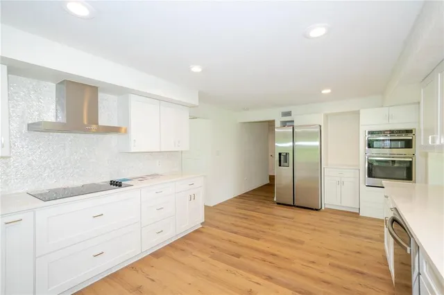 a large white kitchen with granite countertop a sink a window and stainless steel appliances