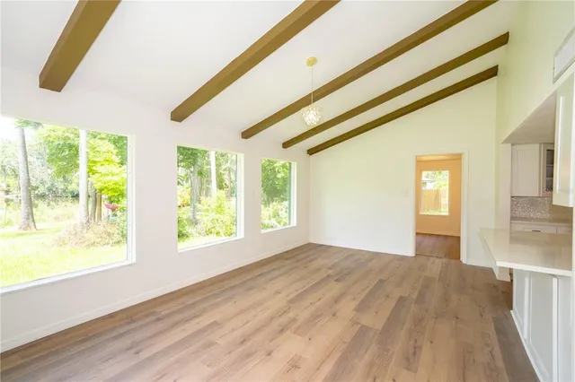 a view of a hallway with wooden floor and a kitchen