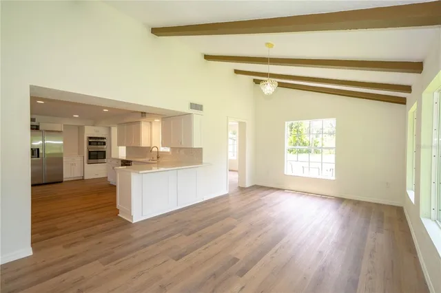 an empty room with wooden floor windows and a ceiling fan