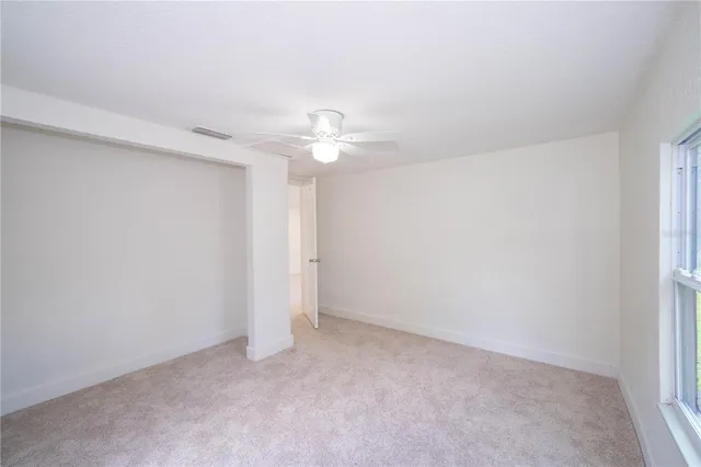 an empty room with a window and a fan