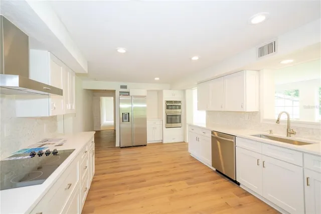 a kitchen with stainless steel appliances kitchen island granite countertop a refrigerator and a sink