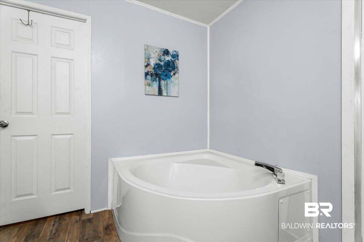 21011 River Road Robertsdale, AL 36567 - Photo 14 of 29 Corner soaking tub with polished chrome fixtures and wood-finish flooring