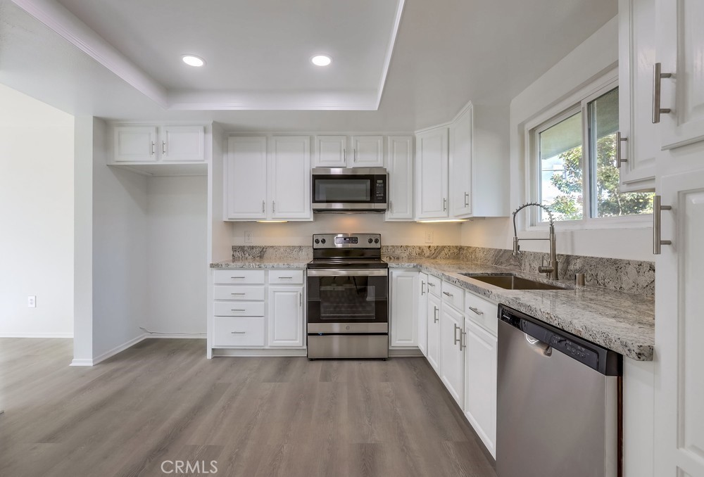 5429 Cajon Avenue Buena Park, CA 90621 - Photo 6 of 22 a kitchen with granite countertop a stove top oven a sink and dishwasher with wooden floor