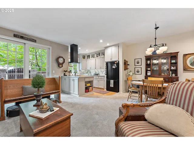 a living room with furniture kitchen view and a large window