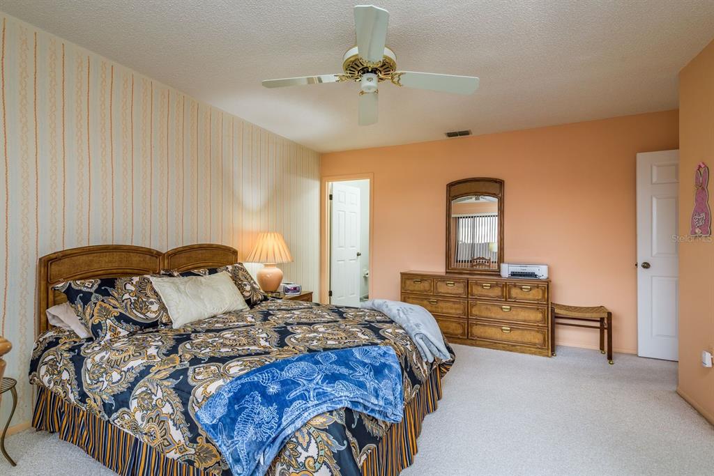 9910 Eagles Point Circle, Unit 3 Port Richey, FL 34668 - Photo 17 of 25 a bedroom with bed and a chandelier