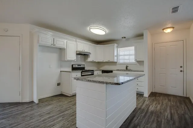 a kitchen with granite countertop a sink cabinets stainless steel appliances and a window