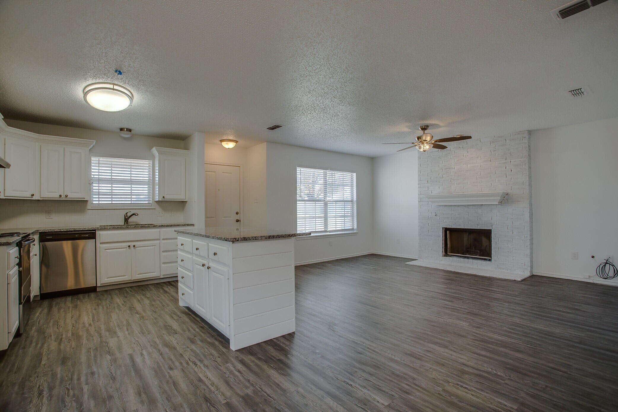 2514 108th Drive Lubbock, TX 79423 - Photo 9 of 16 a kitchen with granite countertop a stove top oven a sink dishwasher and a fireplace with wooden floor