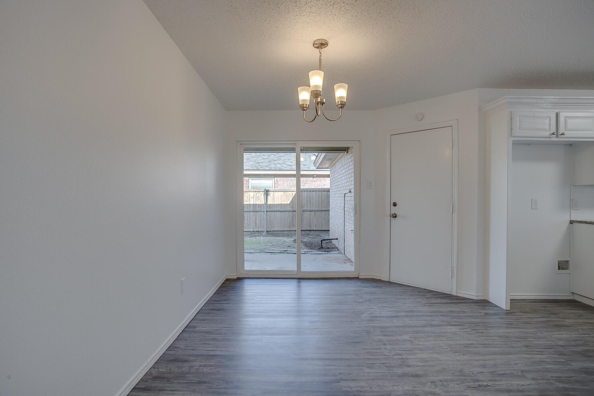 2514 108th Drive Lubbock, TX 79423 - Photo 10 of 16 an empty room with wooden floor chandelier and windows